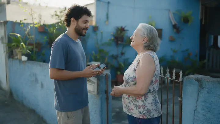 Inquilino conversando com calma com a dona da casa no portão, junto a um muro azul com plantas