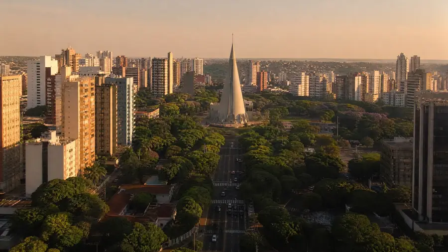 Vista de Maringá ao entardecer, com prédios, avenida arborizada e a catedral em forma de cone (imagem ilustrativa)