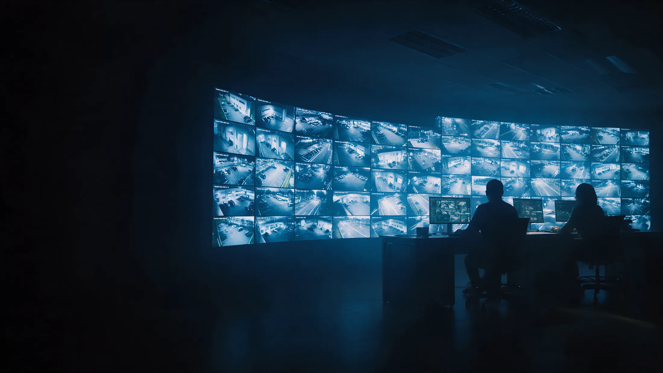 Central de monitoramento 24 horas com painel de câmeras e operadores à noite