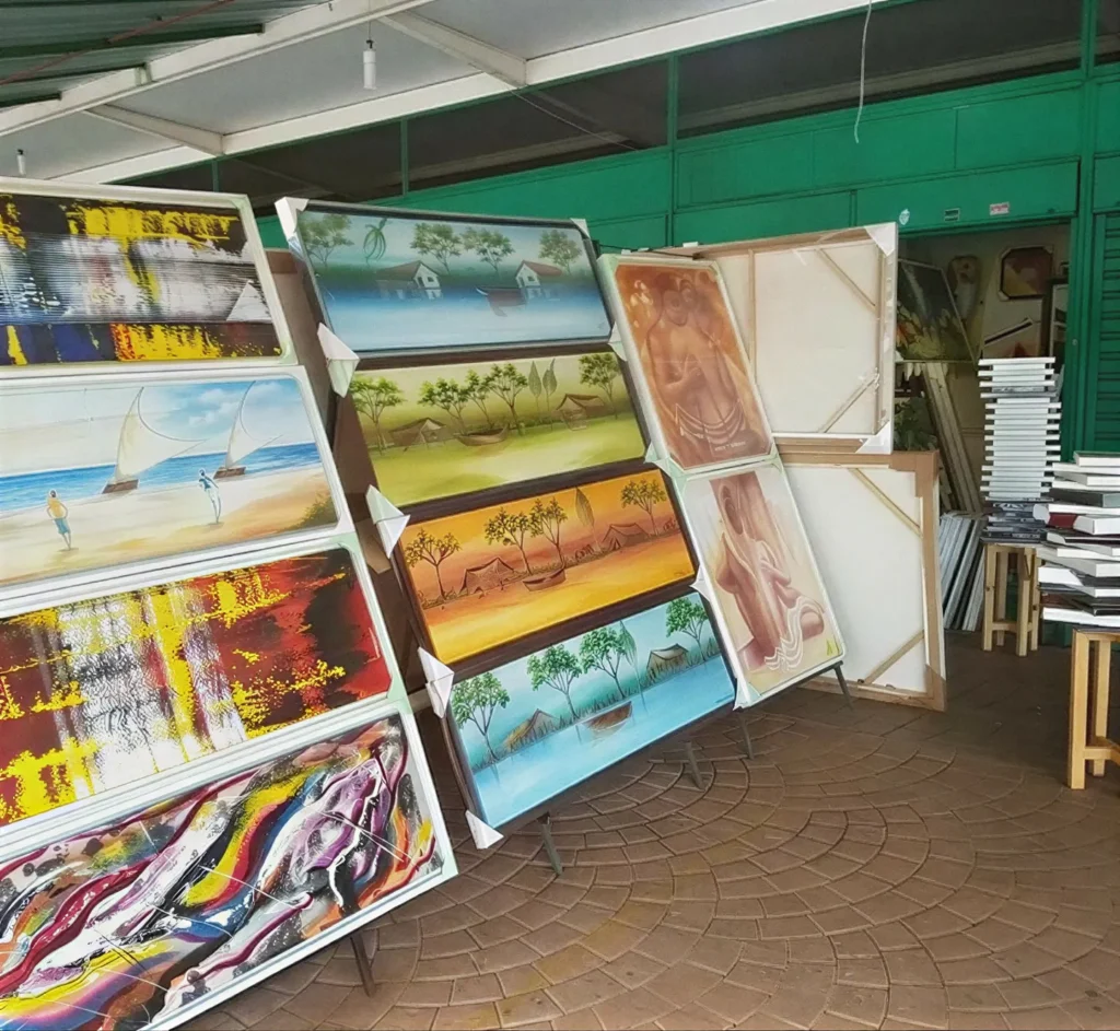 Quadros a óleo expostos em cavaletes numa feira coberta