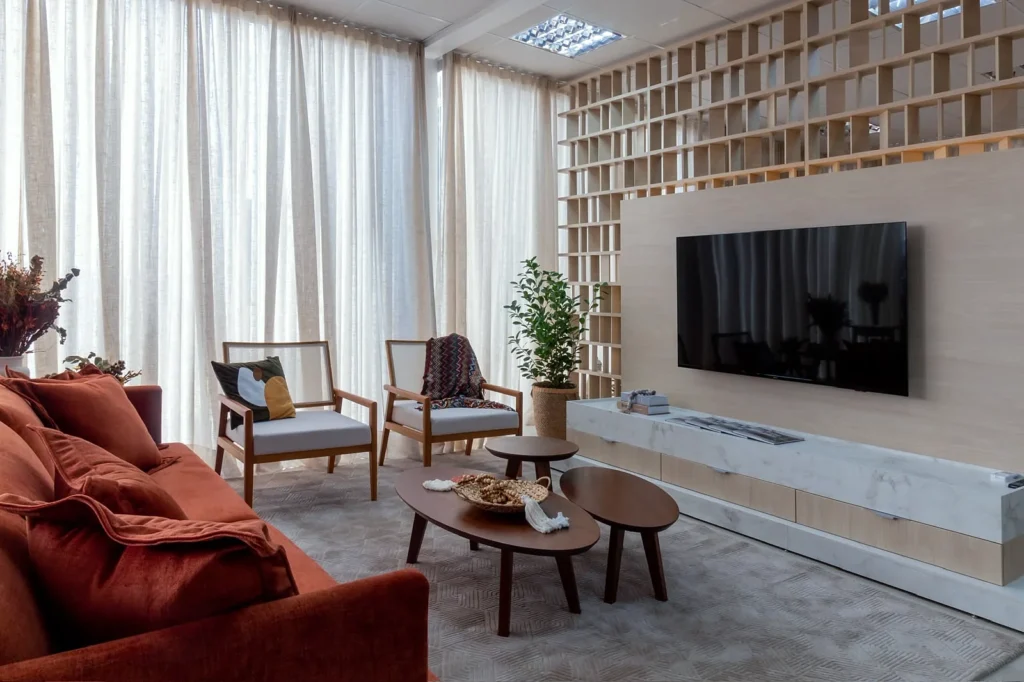 Sala de estar com painel de TV, rack em pedra e estante vazada em madeira clara