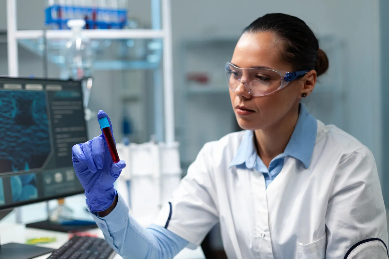 Pesquisadora conferindo tubo de coleta de sangue no laboratório