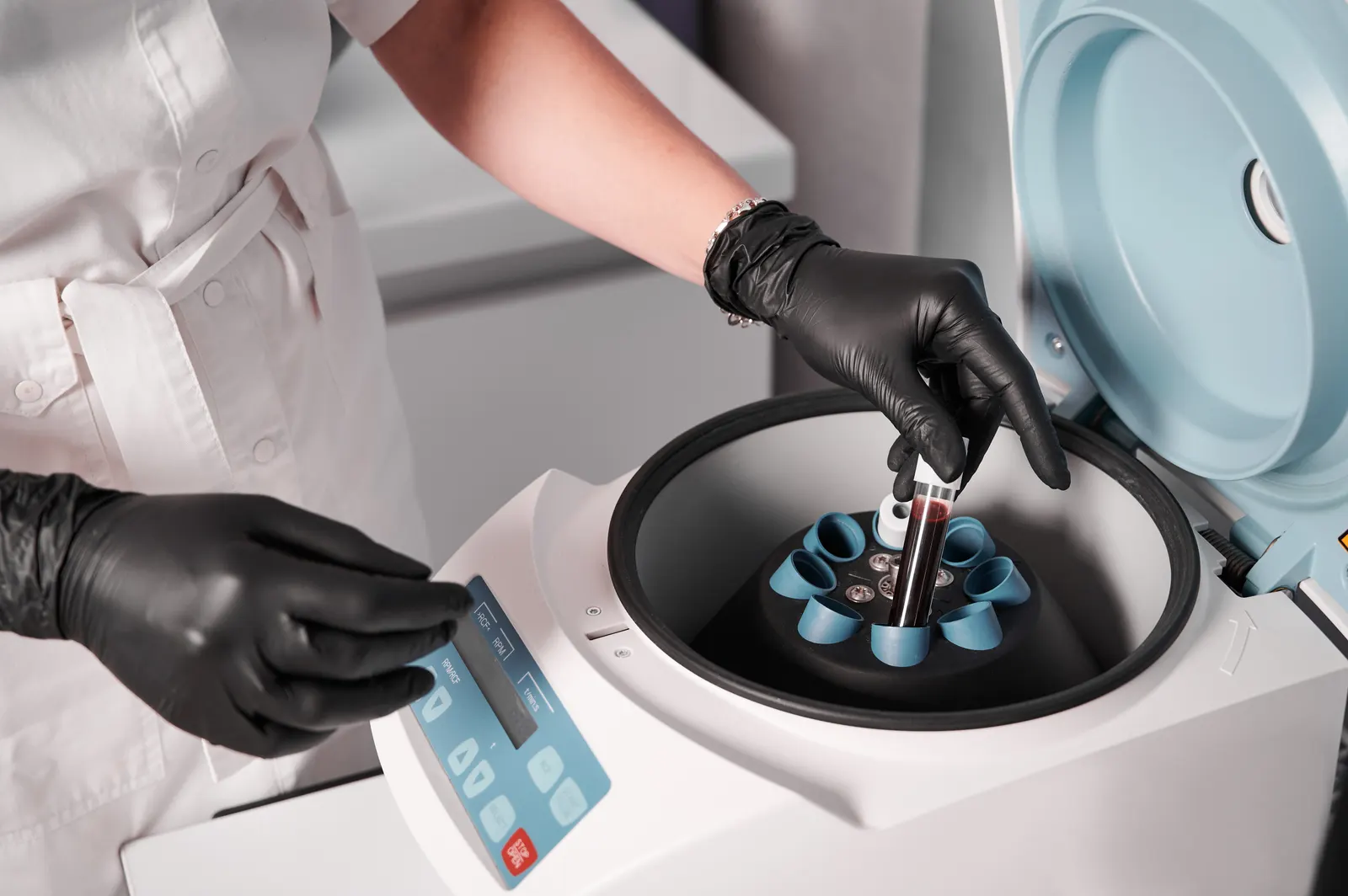 Biomédica colocando tubo de amostra na centrífuga do laboratório clínico