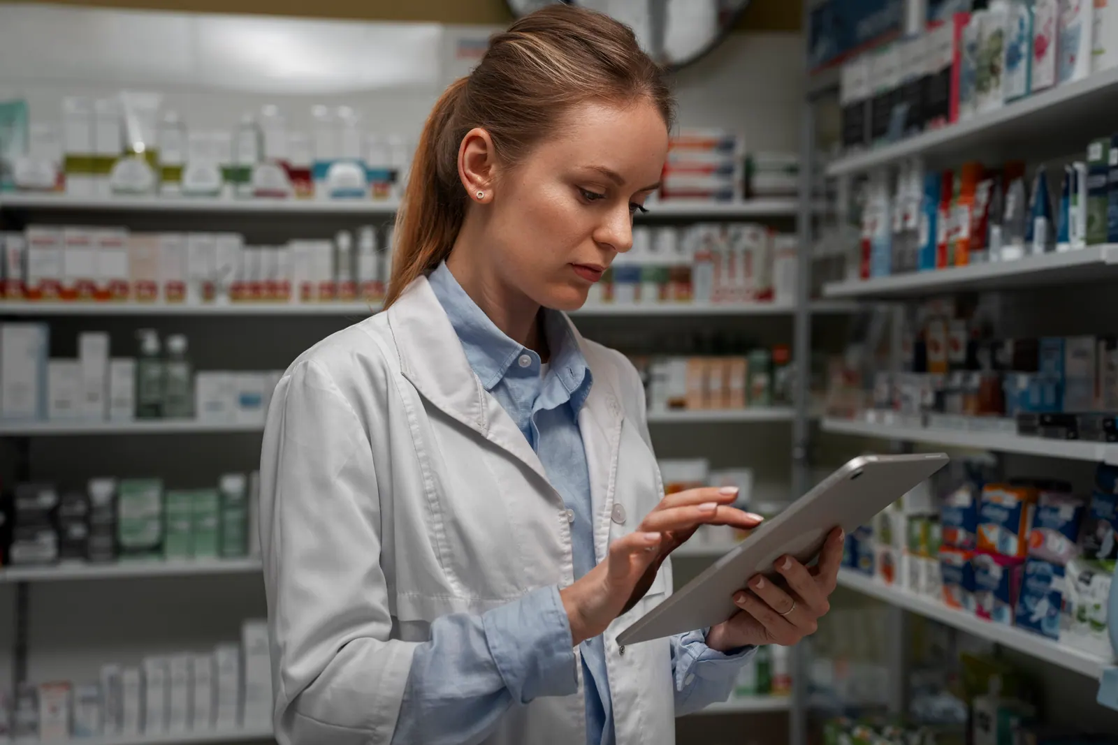 Farmacêutica conferindo o estoque de medicamentos no tablet