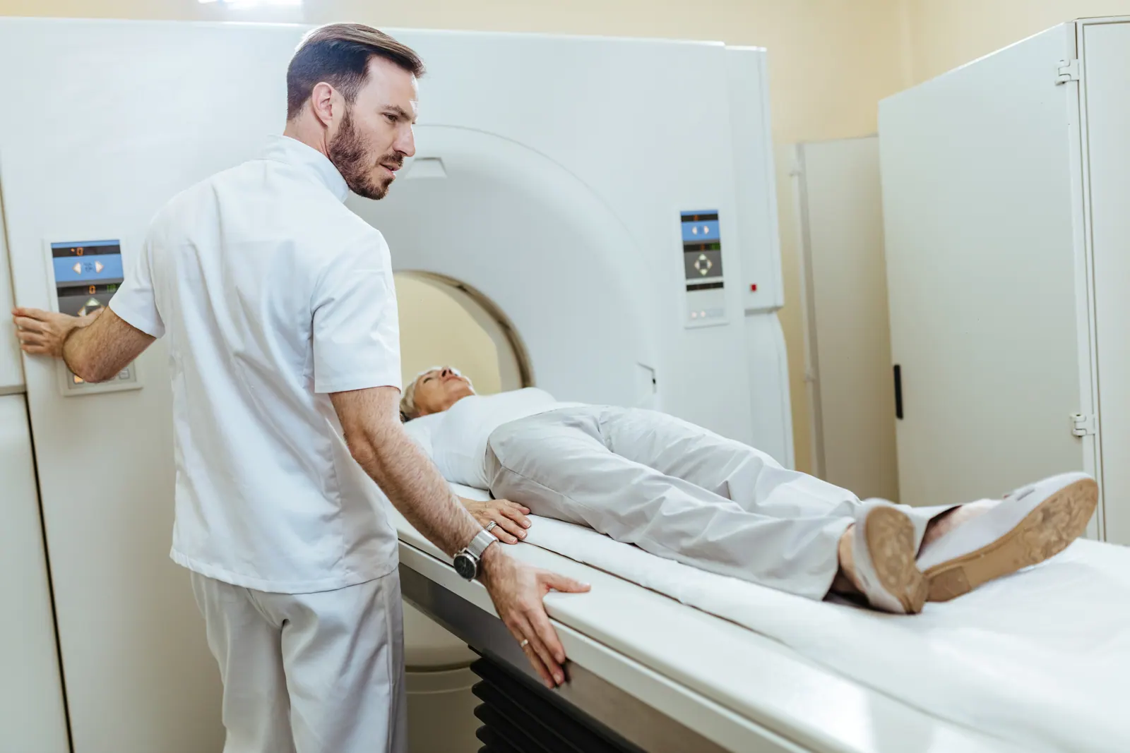Técnico de radiologia iniciando exame de ressonância magnética em paciente