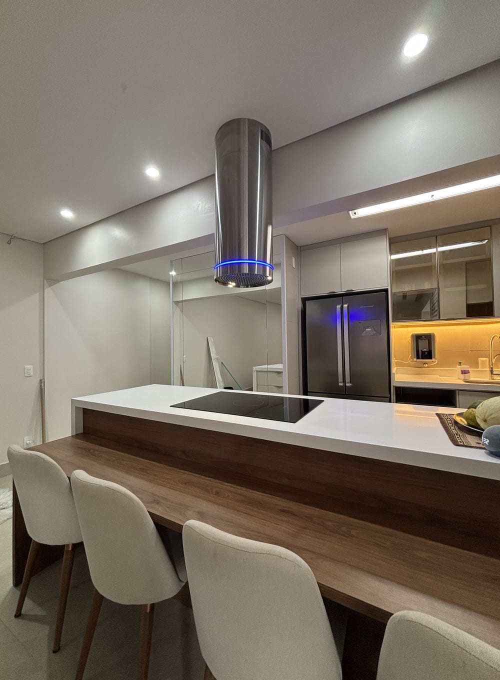 Cozinha com ilha, coifa e bancada de madeira com banquetas
