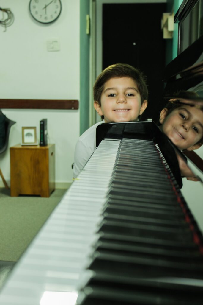 Aluno sorrindo atras do piano do studio