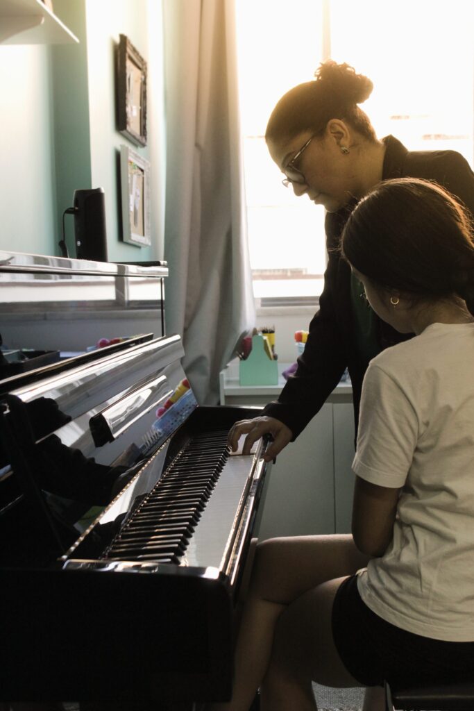 Professora orientando aluna ao piano