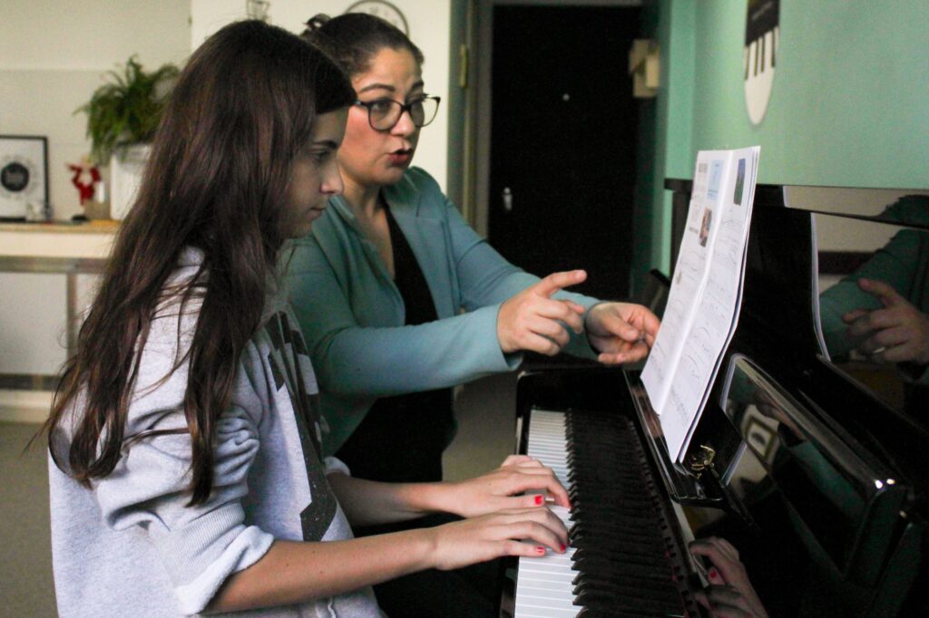 Professora orientando aluna ao piano no studio