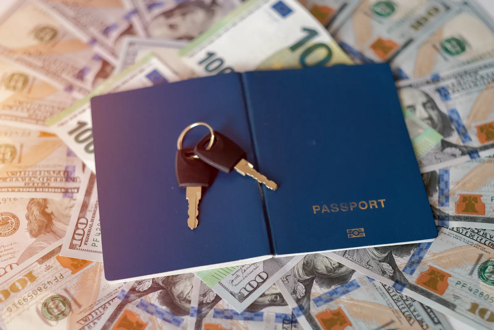 Passaporte com chaves de imóvel sobre notas de dólar