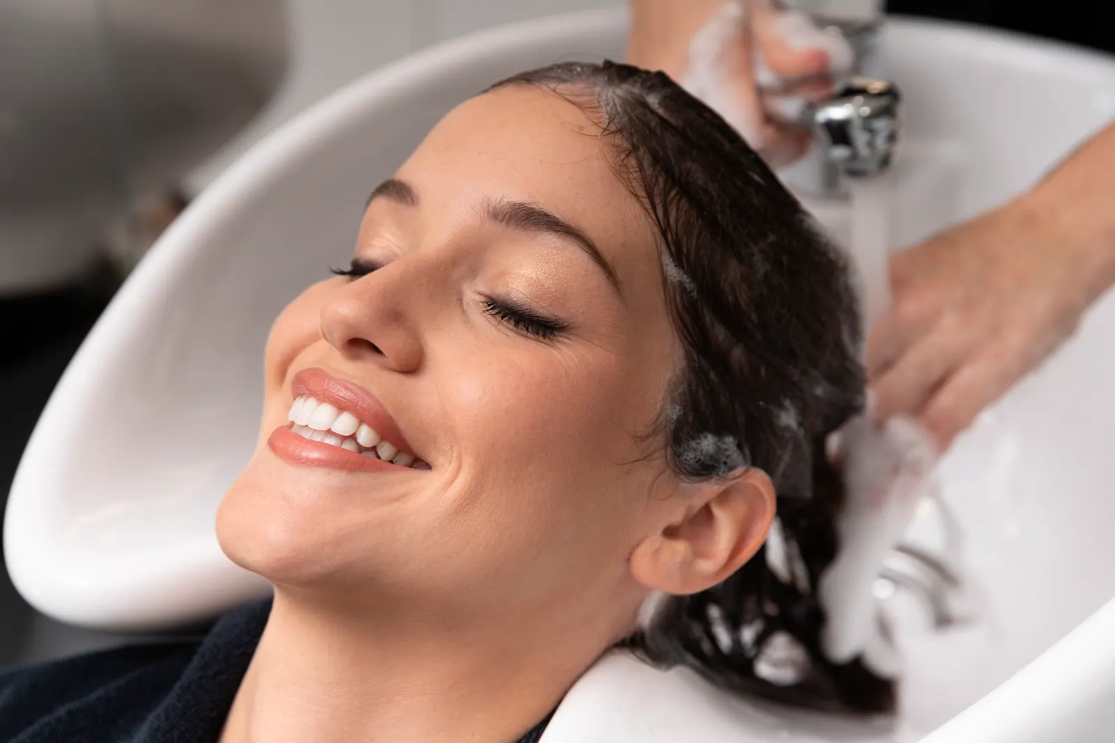 Cliente sorrindo durante lavagem e hidratação no salão