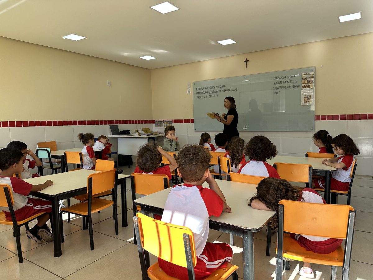 Crianças da Pré-escola às mesas, acompanhando a professora