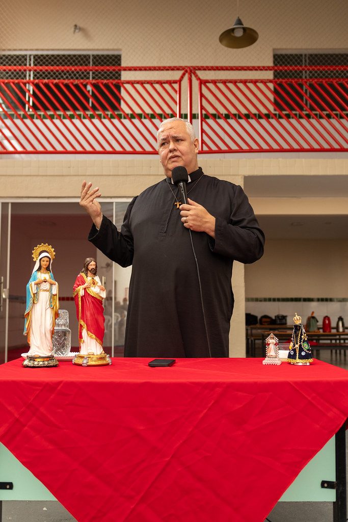 Padre fala às famílias na Primeira Missa Escolar, diante das imagens de Nossa Senhora e do Sagrado Coração