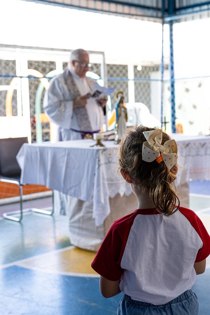 Aluna de uniforme acompanha a celebração da missa