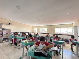 Aluno do Fundamental com o livro aberto na carteira, em sala de aula