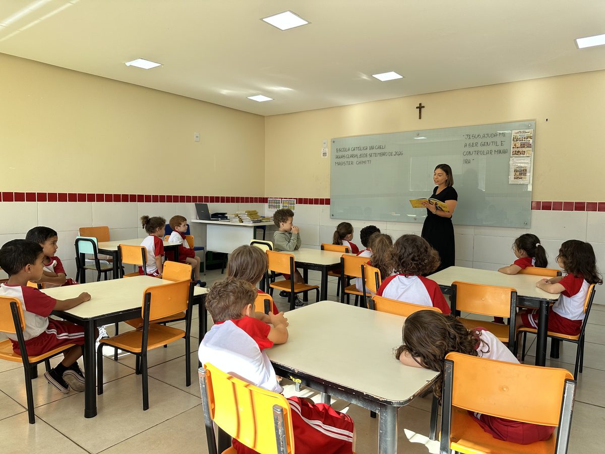 Turma da Pré-escola às mesas, com a professora ao quadro