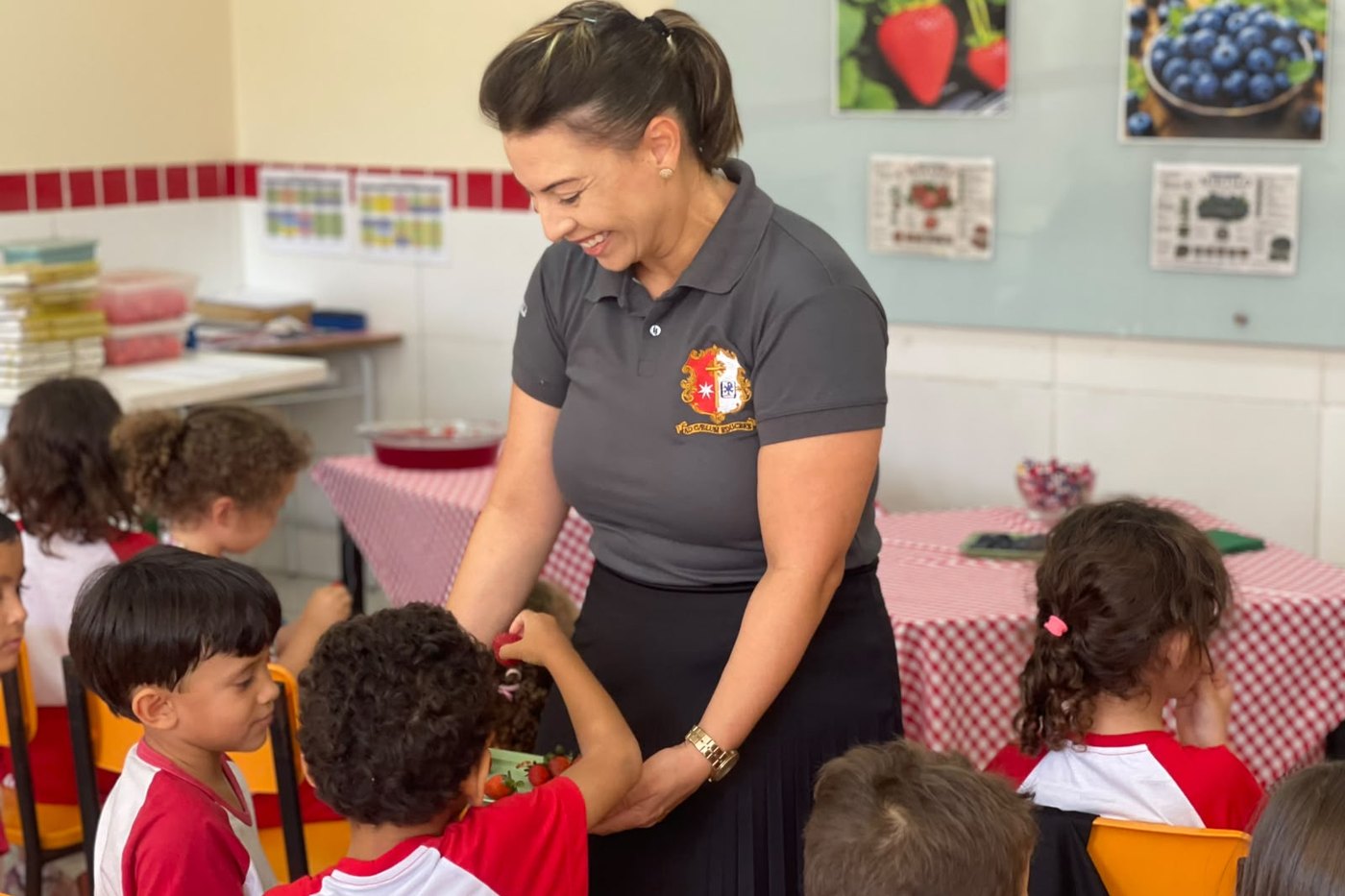 Professora da Via Cæli entregando morangos aos alunos