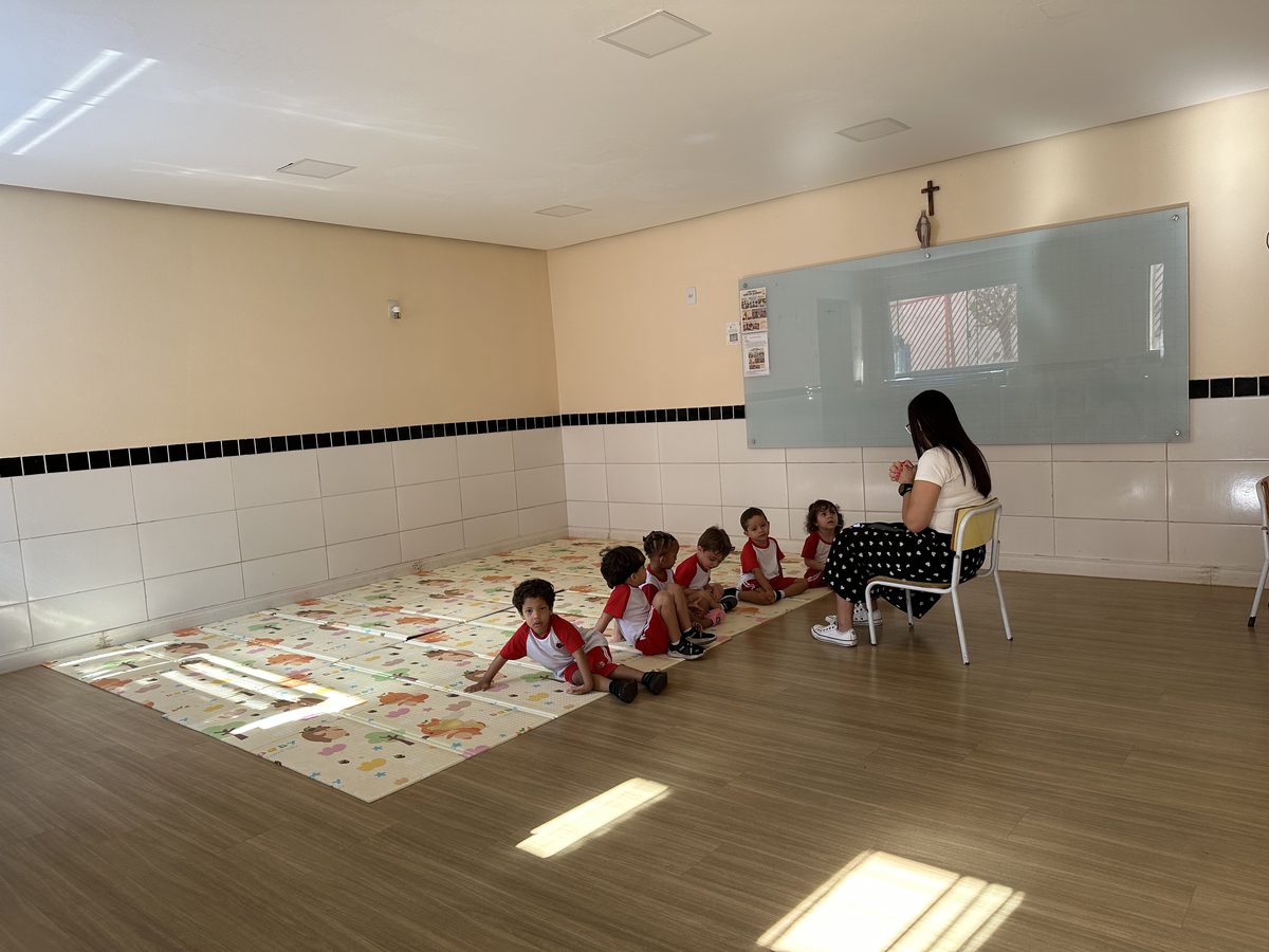 Professora em roda com as crianças sobre o tatame da sala